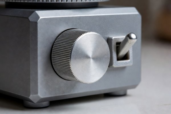 Close-up of a knurled aluminum control dial and physical toggle switch on a compact countertop appliance